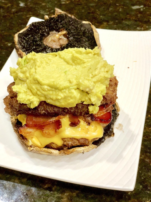 Cajun double cheeseburger with bacon, chipotle aioli avocado mash, on top of a portabello bun