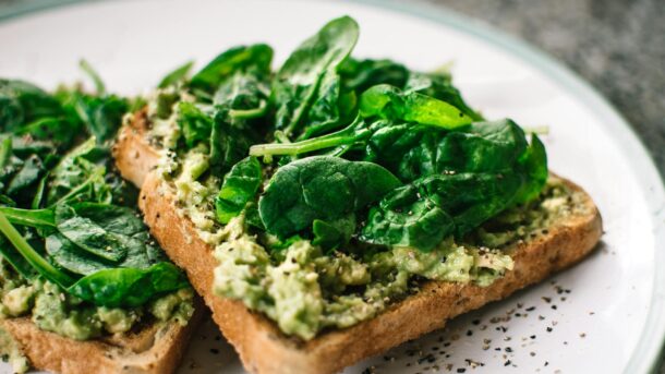 basil leaves and avocado on sliced bread on white ceramic plate